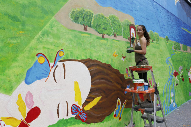 R.Grobas. Mural coa artista María Romero no seu último día de traballo. Fachada do Colexio Niño Jesús de Praga que da á rúa Rosalía de Castro.